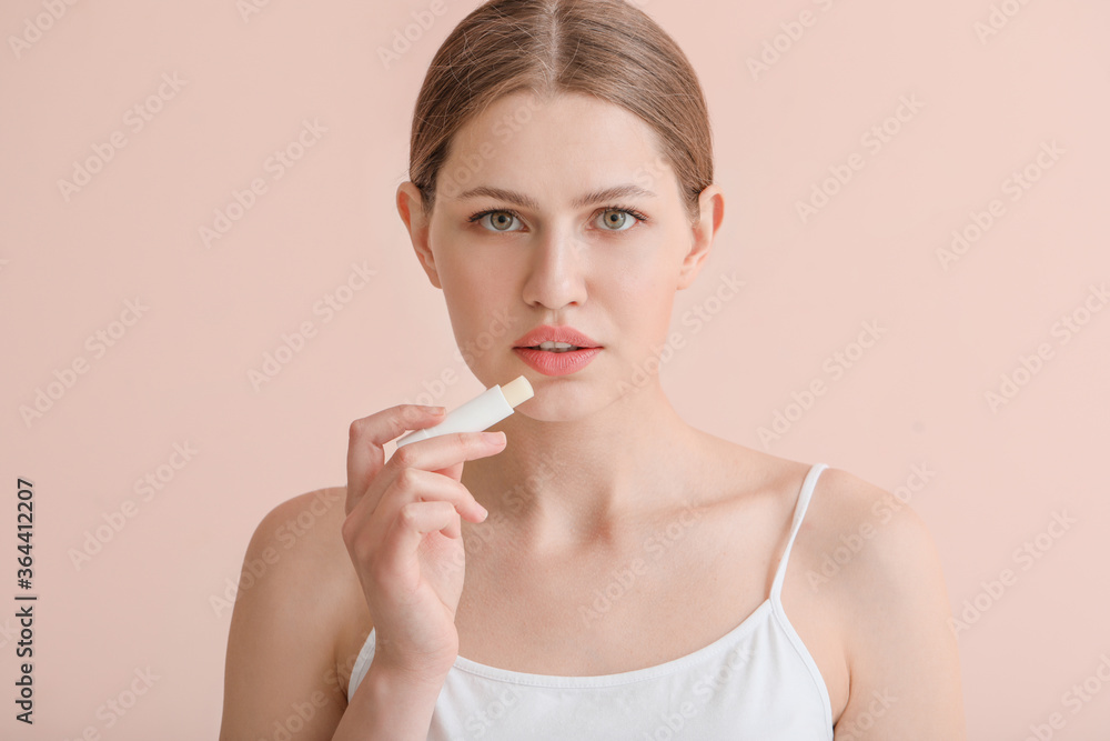 Beautiful young woman with lip balm on color background Beautiful young woman with lip balm on color background