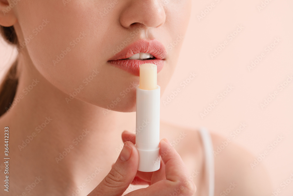 Beautiful young woman with lip balm on color background, closeup - obrazy, fototapety, plakaty 