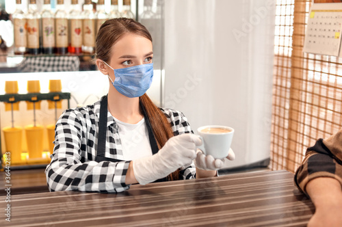 Barista in mask giving coff...