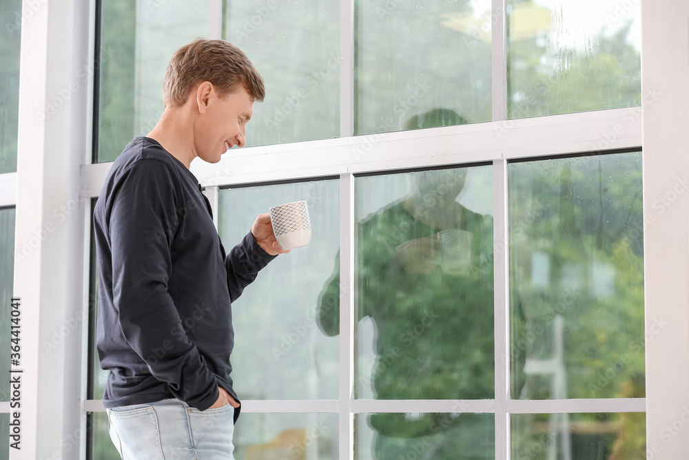 Handsome man drinking tea near window Handsome man drinking tea near window