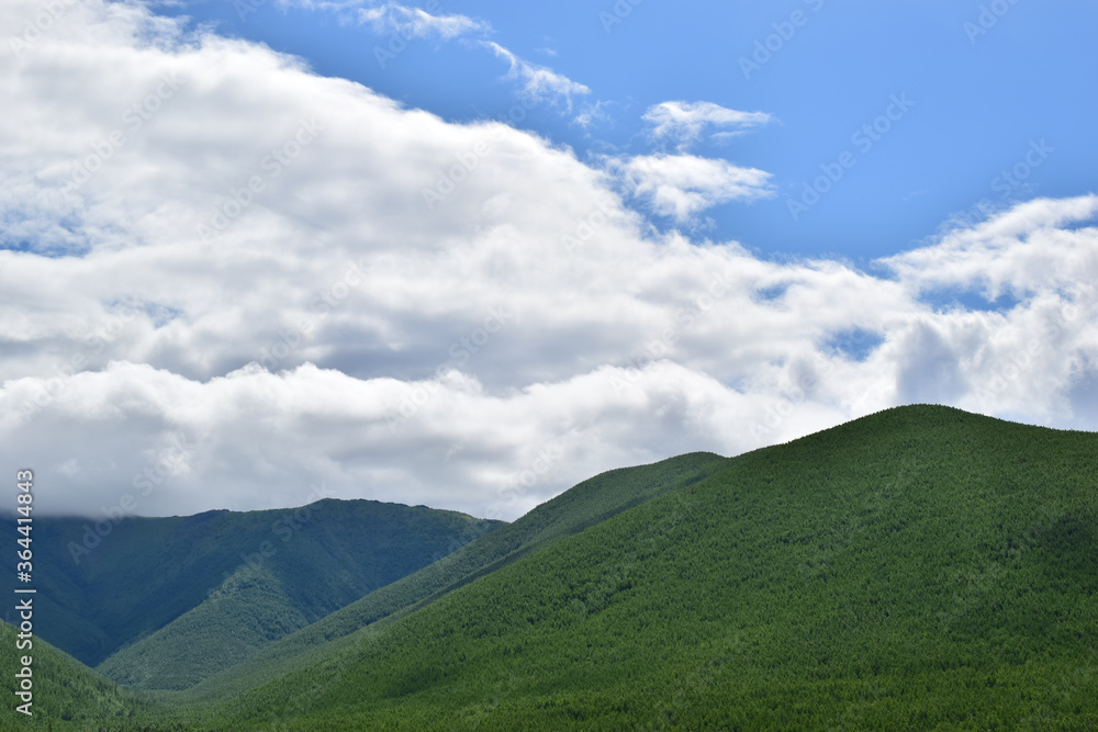 Green hills of Sikhote-Alin. Summer day with white clouds and blue sky. Green hills of Sikhote-Alin. Summer day with white clouds and blue sky.