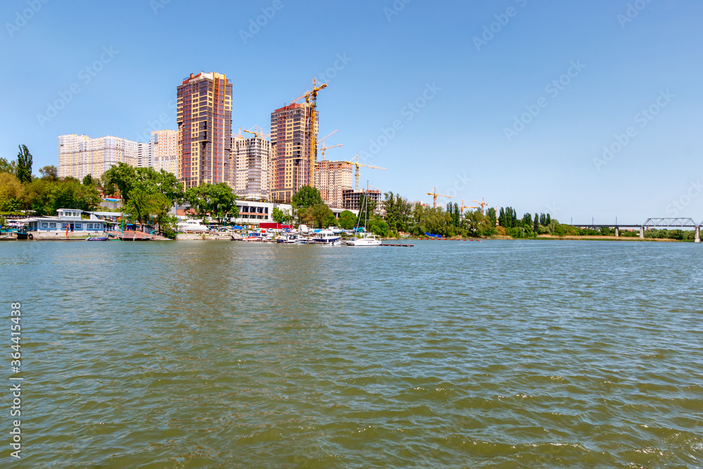 New modern multi-storey residential buildings on the side of a river and the boat parking near it. Don river, Rostov-on-Don, Russia