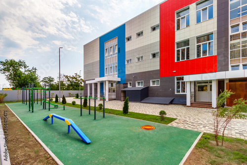 The children's fitness playground with the gymnastic sport equipments in front of a new modern school building