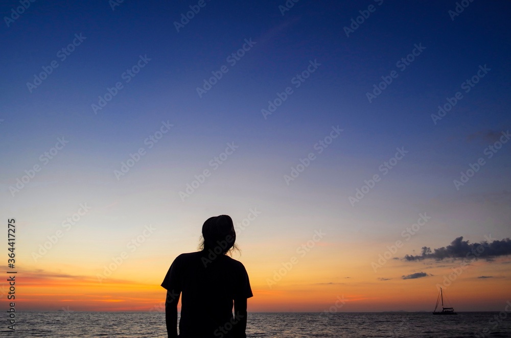 Blurred photo, Silhouette Standing man look at the ship floating in the sea and sunset background.