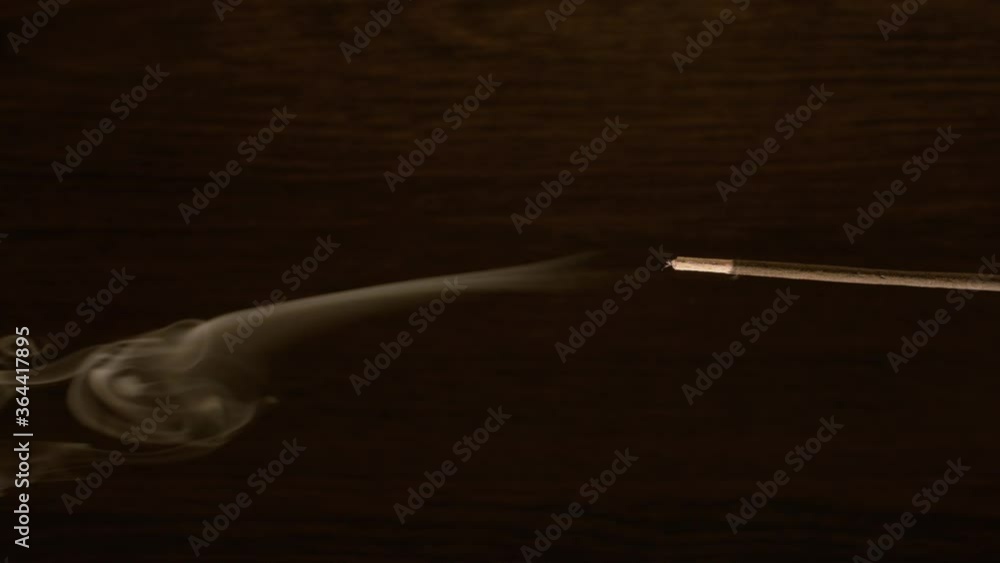 Close-up of incense smoke on a wooden dark background in the room. Close-up of incense smoke on a wooden dark background in the room.
