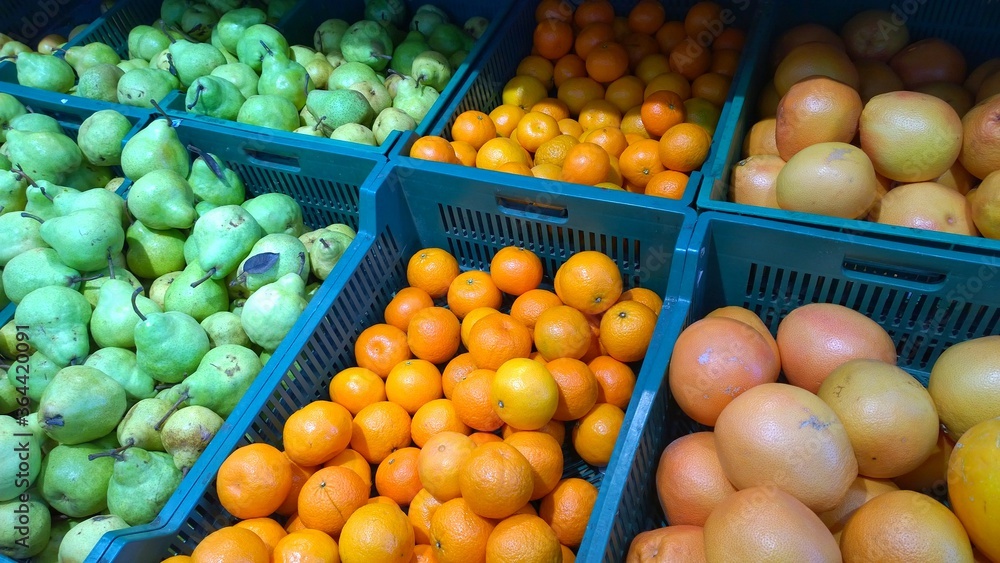 Fresh fruits, green pears, oranges, grapefruits on supermarket shelves. Retail industry. Farmers market. Discount. Problem of rising food prices. Rich harvest. Grocery store. Healthy organic products.