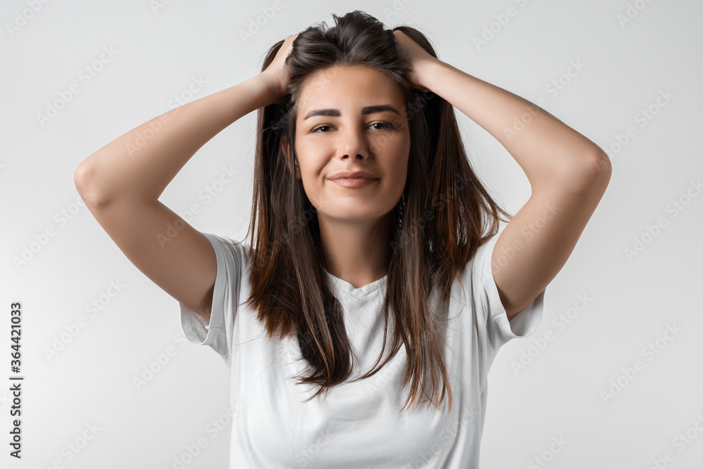 Pretty carefree modern girl with long chestnut hair holding to her head or touching hair. Isolated on white background. Emotions, expressions, hairstyle and people concept. Pretty carefree modern girl with long chestnut hair holding to her head or touching hair. Isolated on white background. Emotions, expressions, hairstyle and people concept.