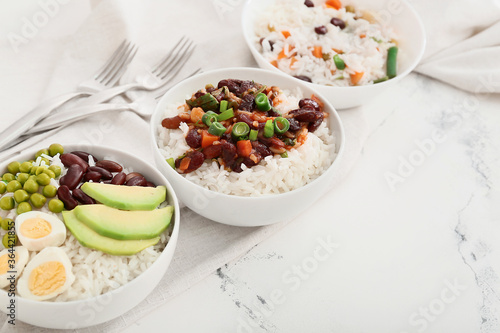 Bowls with tasty rice, beans and vegetables on table