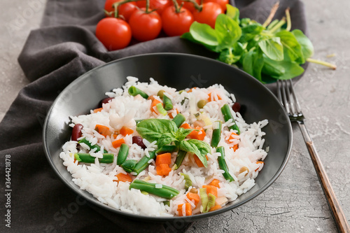 Bowl with tasty rice, beans and vegetables on grunge background