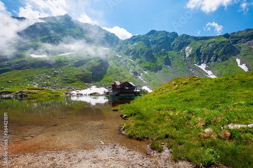 clouds above balea lake in romania. stunning summer landscape in fagaras mountains. scenery reflecting in crystal clear water on a sunny day.