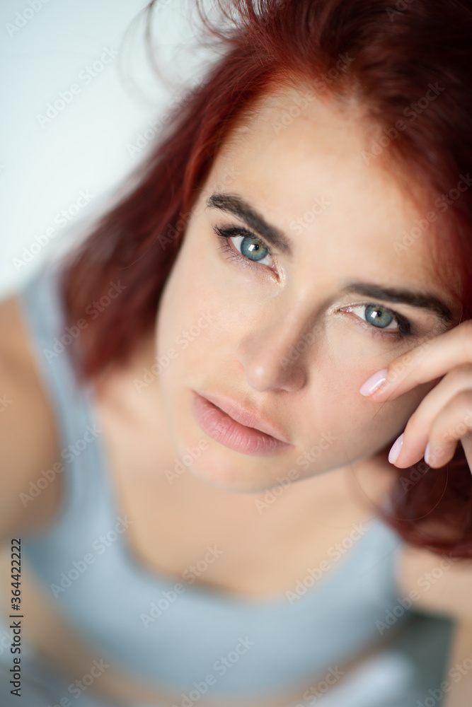 Beautiful young ginger woman with blue eyes. Portrait of charming girl wearing casual clothes posing at home, looking at camera Beautiful young ginger woman with blue eyes. Portrait of charming girl wearing casual clothes posing at home, looking at camera