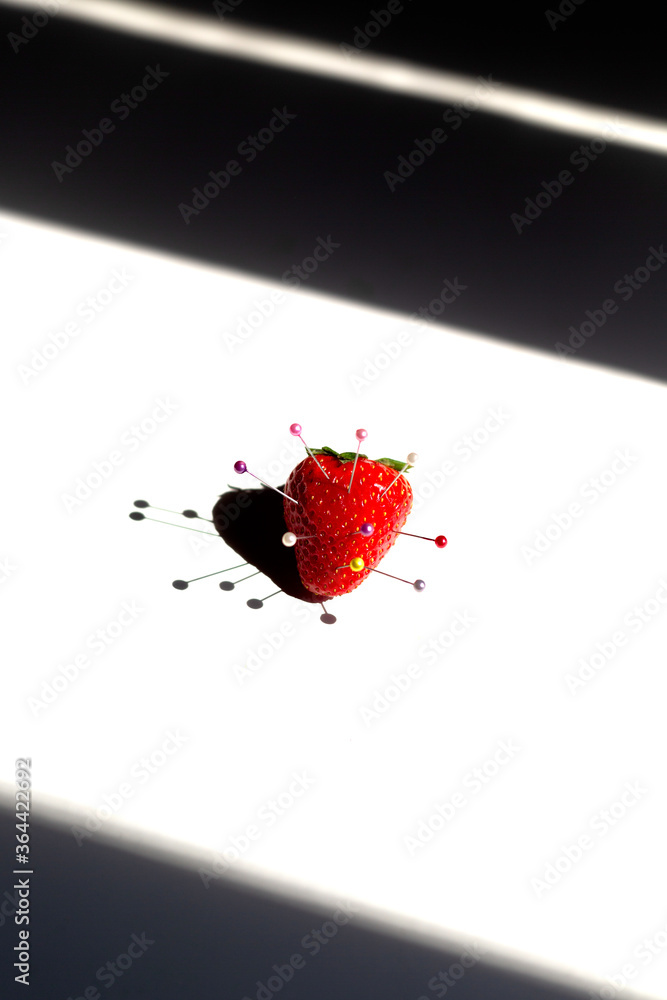 strawberry with stapled pins, on a white background, strong light strawberry with stapled pins, on a white background, strong light