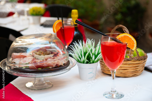 Aperitif in Italy. Delicious tasty traditional italian food and drink. Prosciutto, cheese, olives and cocktail in outdoor restaurant, cafe or pizzeria.