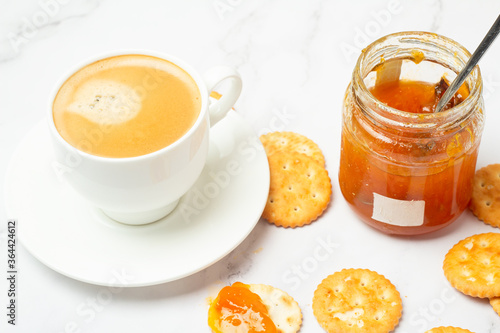 apricot jam in a jar and black coffee close-up.