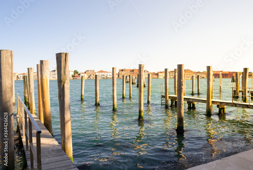 Venice, Italy. Typical landscape view of the lagoon, rawn of mooring poles in perspective with the peculiar venetian architecture in the background.