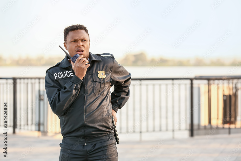 African-American police officer with two-way radio outdoors African-American police officer with two-way radio outdoors
