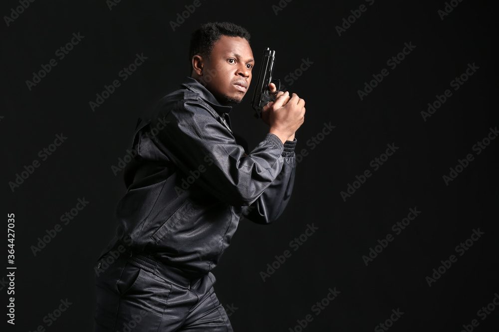 African-American police officer with gun on dark background African-American police officer with gun on dark background