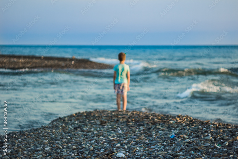 seascape in defocus with the child in the center of the frame; blurred background