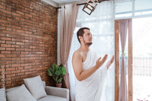 Muslim man praying wearing ihram clothes open his arm before going umrah or hajj photo