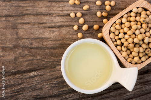 Soy bean oil with soybean seeds in   bowl isolated on rustic wood table background. Top view. Flat lay. 