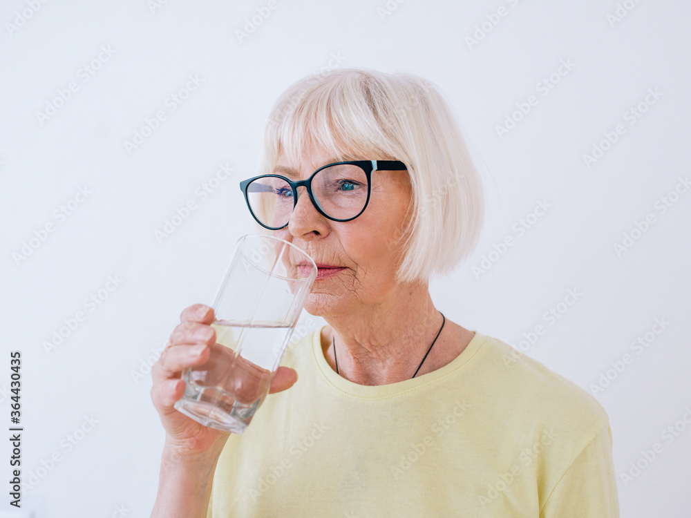 senior woman holding glass of water and drinking water. Healthy lifestyle, sport, anti age concept senior woman holding glass of water and drinking water. Healthy lifestyle, sport, anti age concept