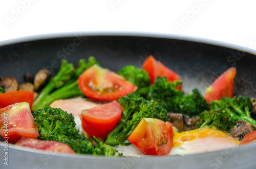 Dish of broccoli mushrooms tomatoes and eggs in a pan
