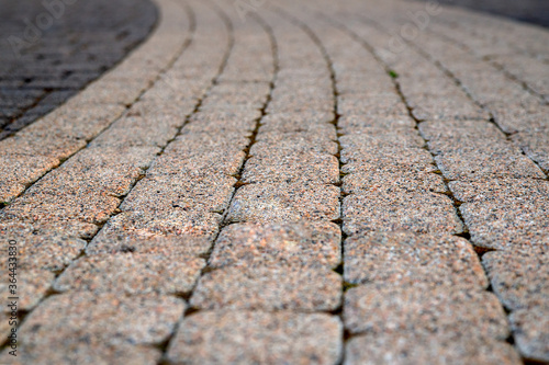 Texture of gray and yellow patterned paving tiles on the ground of street, perspective view. Cement brick squared stone floor back. Design, background. Blurred image, selective focus.
