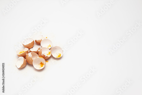Eggshells with yellow and white powder symbolizing unhealthy food and mass production, white background