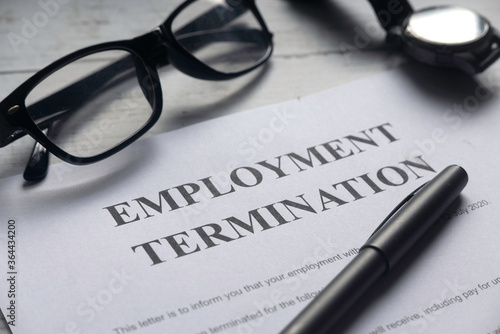 Selective focus of glasses,watch,pen and Employment Termination letter on a white wooden background.