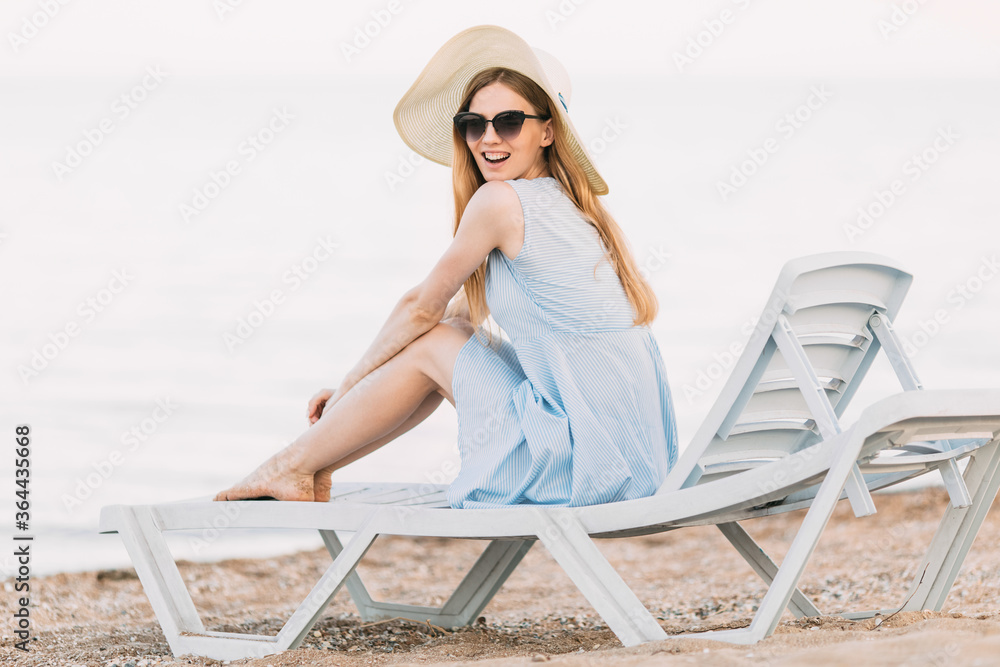 relaxing girl in a summer hat, resting on a sandy beach, lies on a chaise longue. Summer vacation, travel, sea relaxing girl in a summer hat, resting on a sandy beach, lies on a chaise longue. Summer vacation, travel, sea
