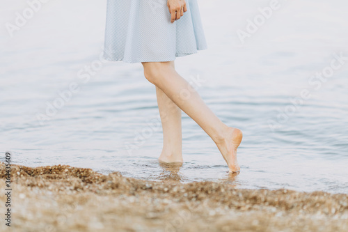 Close-up of female feet, a woman walking on a sandy beach, leaving footprints in the sand. Summer vacation