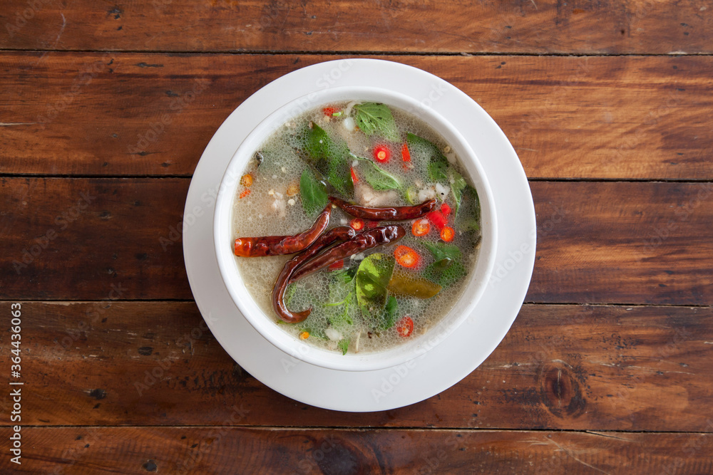 Thai food spicy soup with pork bone on wood background Thai food spicy soup with pork bone on wood background