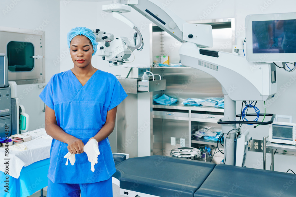Obraz premium Young Black surgeon putting on rubber gloves when getting ready for surgery