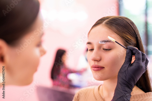 Permanent make-up for eyebrows of beautiful woman with thick brows in beauty salon. Professional makeup and cosmetology skin care.