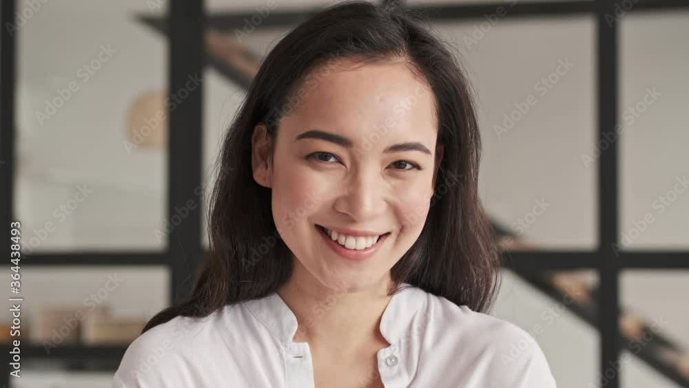 Smiling elegant pretty asian woman becoming happy and looking at the camera at home