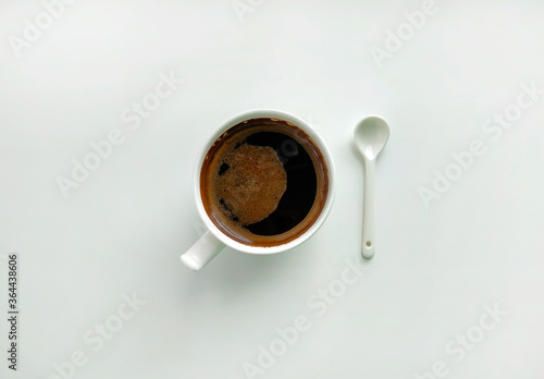 White cup of coffee and white ceramic spoon on a white background