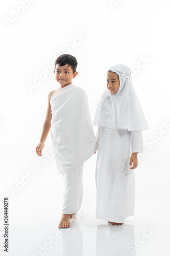 cute little kid wearing muslim ihram clothes and dress holding hand and walk. hajj and umrah concept