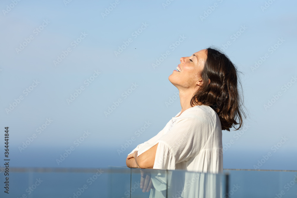 Happy adult woman breathing fresh air on the beach