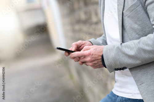 Man standing against a wall and using mobile phone