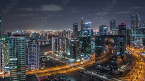 Wallpaper Mural Business bay illuminated towers with parking at night timelapse. Rooftop view of some skyscrapers near canal and new towers under construction with crane. Traffic on roads and lights in windows Torontodigital.ca