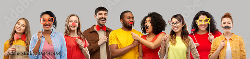 photo booth and fun concept - happy smiling people with party props over grey background photo