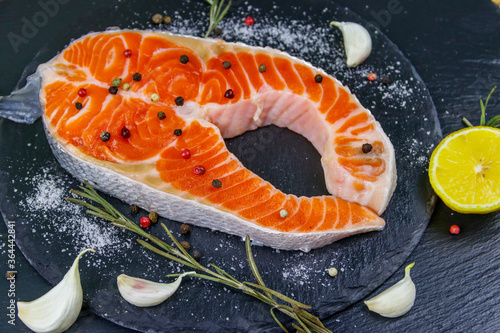 Raw salmon steak with spices on black slate