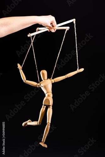 Photo cropped view of puppeteer holding wooden marionette isolated on black