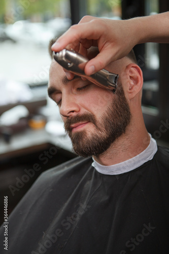 Vertical close up of a man getting his beard trimmed by professional barber