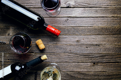 Glasses of red and white wine and bottles on a dark wooden background. Flat lay and top view, copy space for text or design