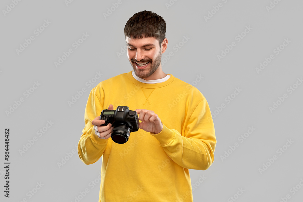 photography and people concept - smiling young man or photographer in yellow sweatshirt with digital camera over grey background photography and people concept - smiling young man or photographer in yellow sweatshirt with digital camera over grey background