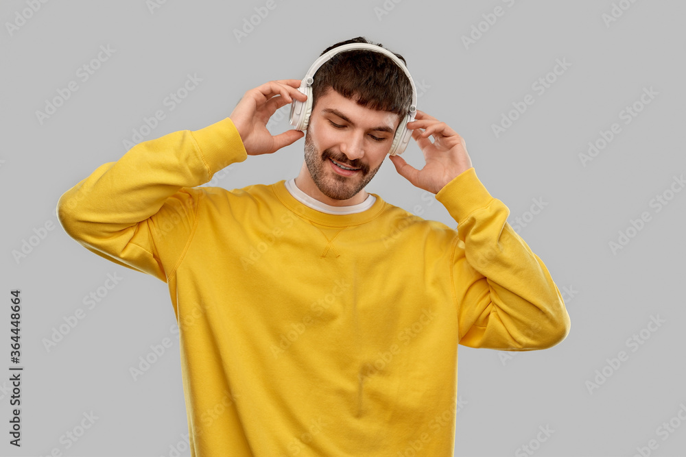 music, technology and people concept - happy smiling young man in headphones over grey background music, technology and people concept - happy smiling young man in headphones over grey background
