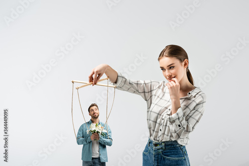 female puppeteer holding male marionette with flowers isolated on grey