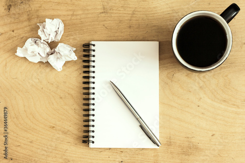 notebook and cup of coffee on wooden desk