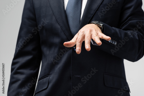 cropped view of businessman in suit manipulating with hand isolated on grey